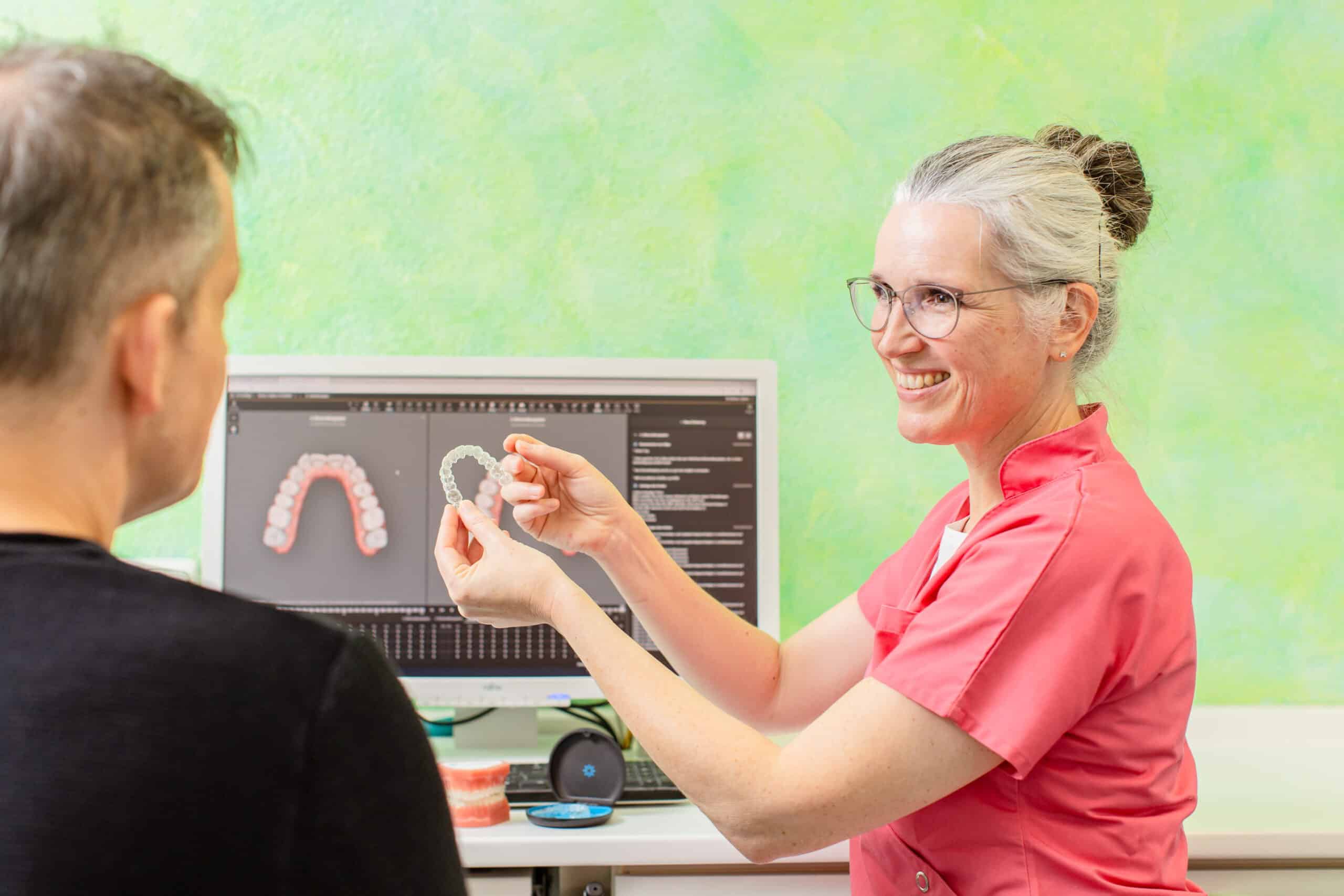 Kieferorthopädin Dr. Kinner erklärt einem Patienten die Aligner-Behandlung