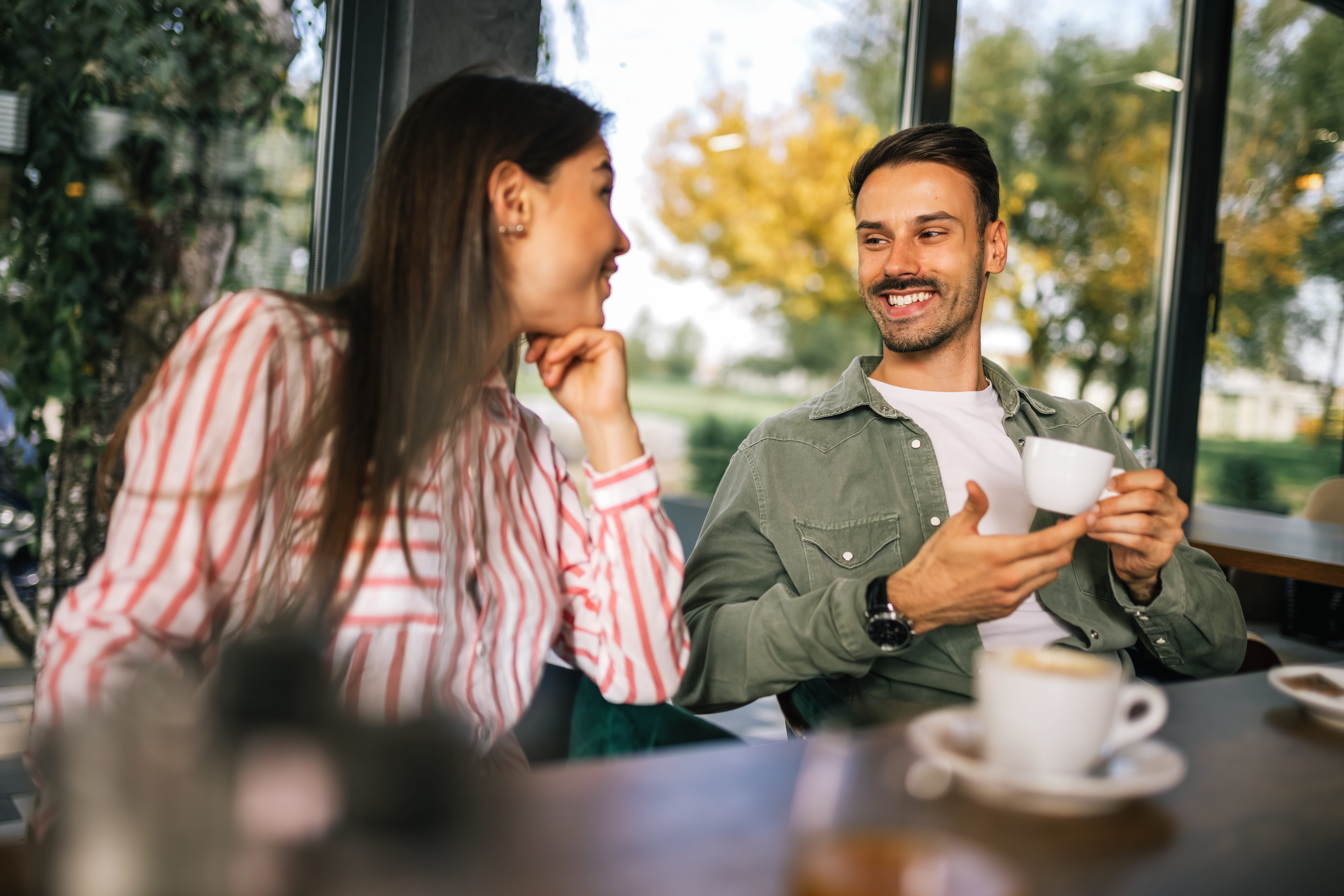Zwei Freunde trinken zusammen Kaffee und unterhalten sich fröhlich