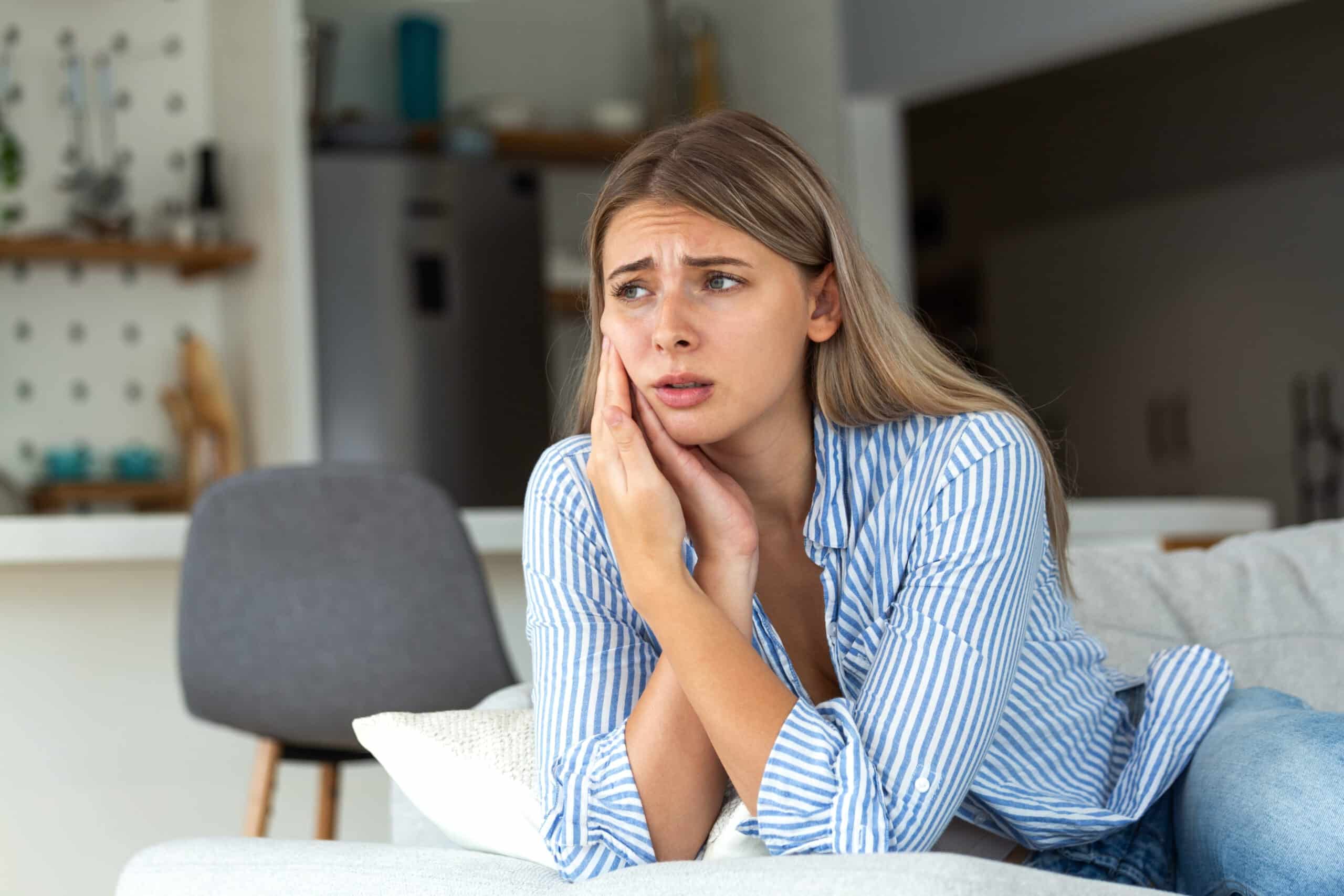 Junge Erwachsene hält sich ihr Gesicht wegen Kieferproblemen